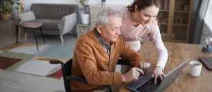 A woman in a wheelchair utilizes a laptop, highlighting the importance of technology for inclusivity and accessibility.