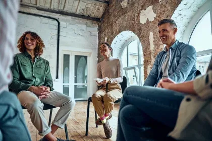 A diverse group of individuals seated in chairs, engaged in conversation and sharing ideas in a relaxed setting.